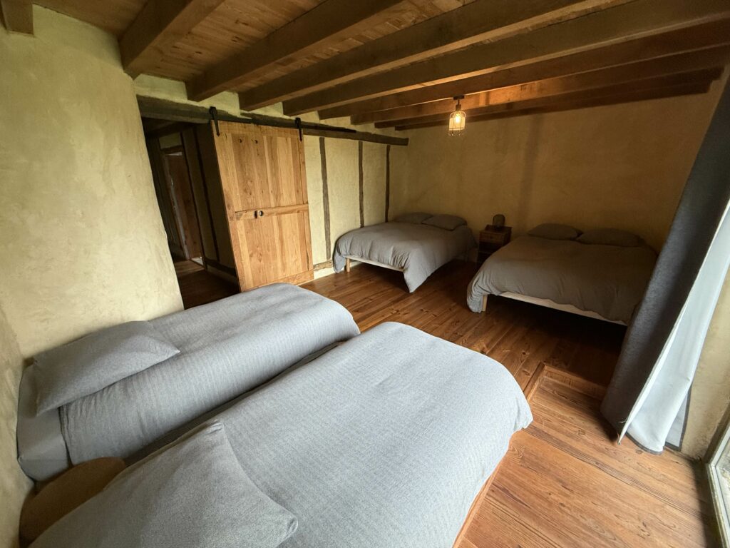Chambre 3 : deux lits doubles et deux lits simples sous les poutres – gîte de groupe