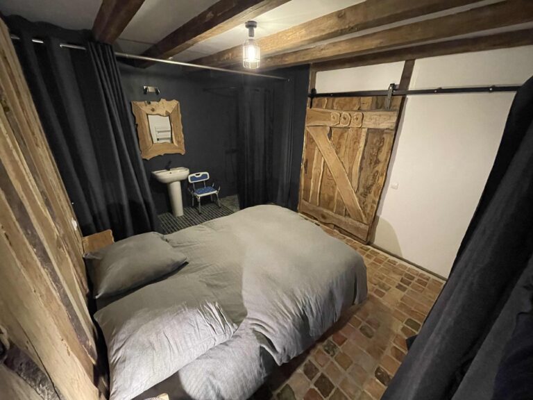 Chambre 1 : lit double, rideau noir et lavabo de la salle d’eau privative