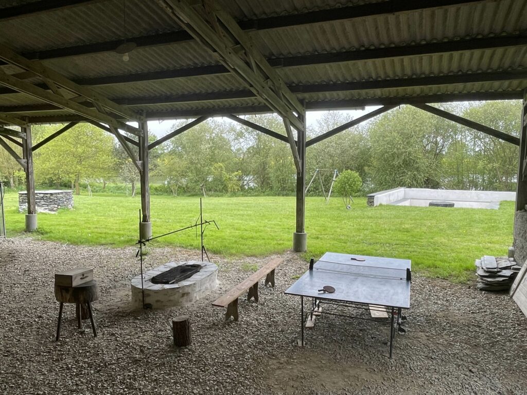 Le hangar ouvert avec le brasero, la table de ping-pong et le jardin