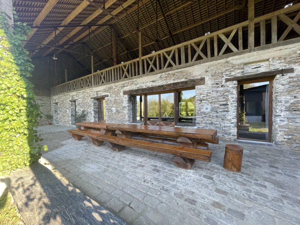 Patio couvert de la longère en schiste avec la grande table en bois massif – photo du gîte de groupe