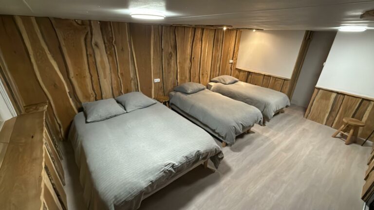 Chambre 7, dans la cabane : un lit double et deux lits simples, mur en chêne brut