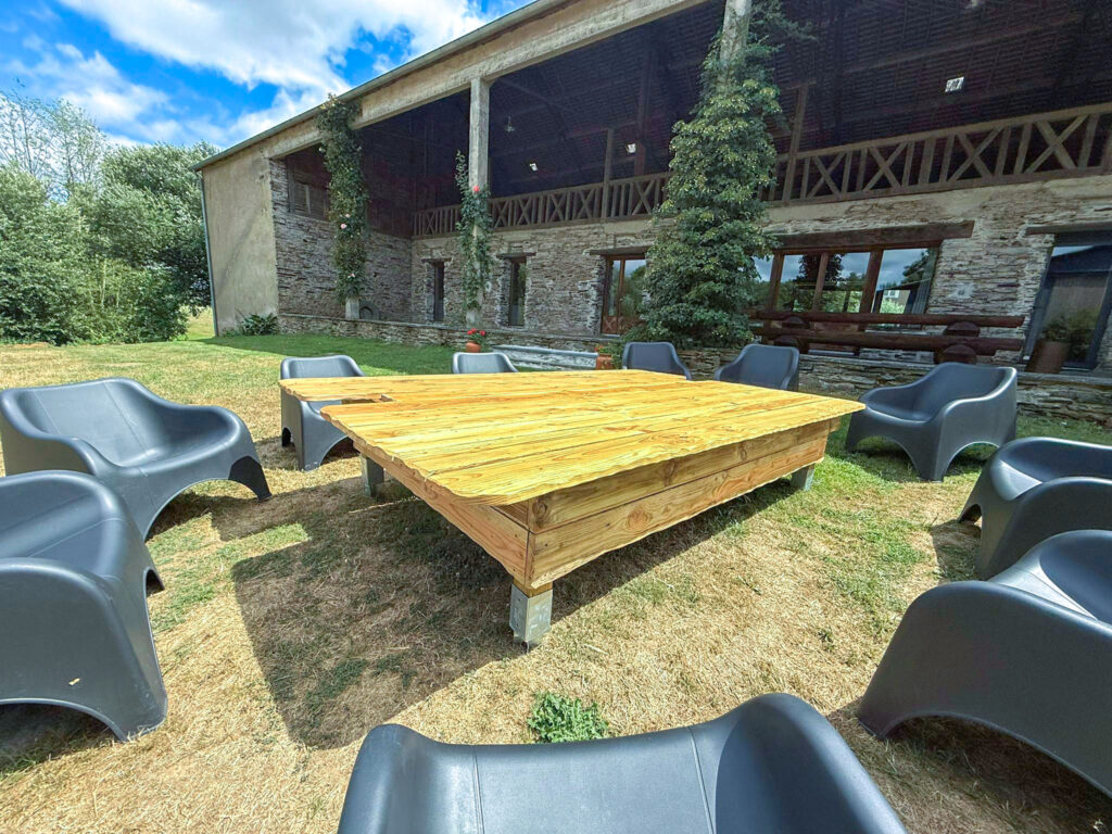 Terrasse en bois et fauteuils de jardin devant la longère
