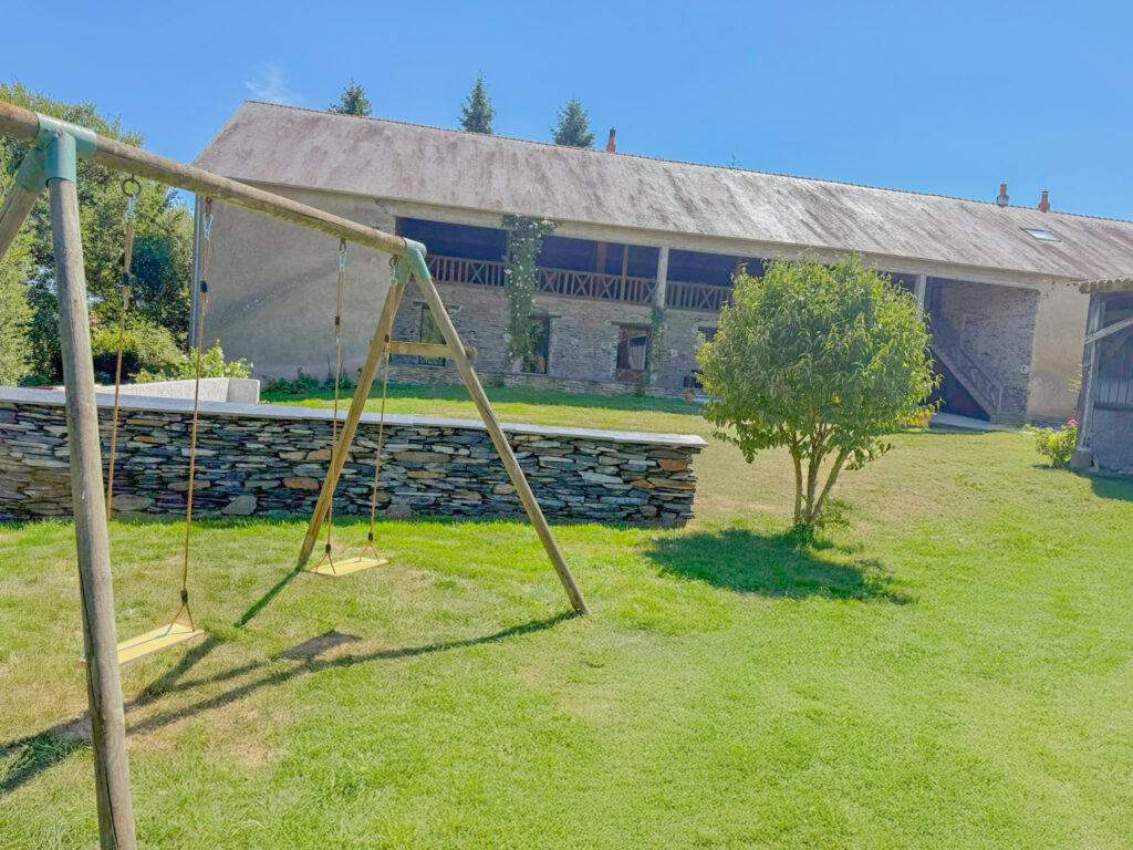 La longère vue du jardin, balançoire et muret en schiste